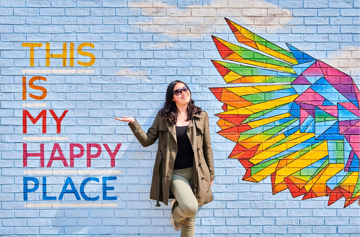 Student poses with a vibrant mural in Durham city.
